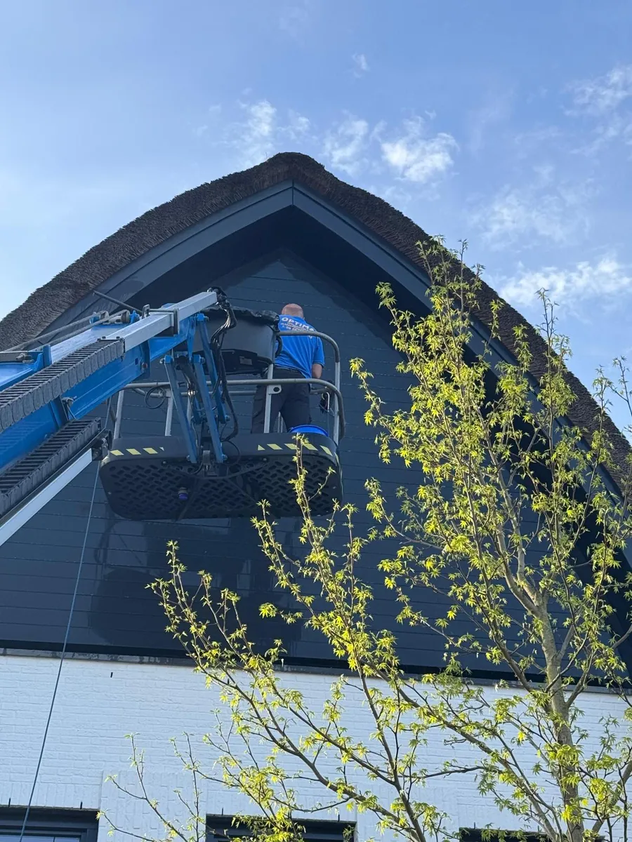 Hoogwerker bij een moderne woning met boogdak